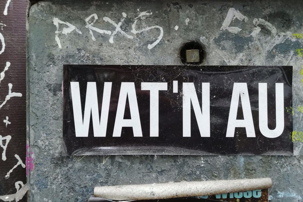Sticker-Art in Köln: Aufkleber an Briefkasten hat die Aufschrift "Wat nau"