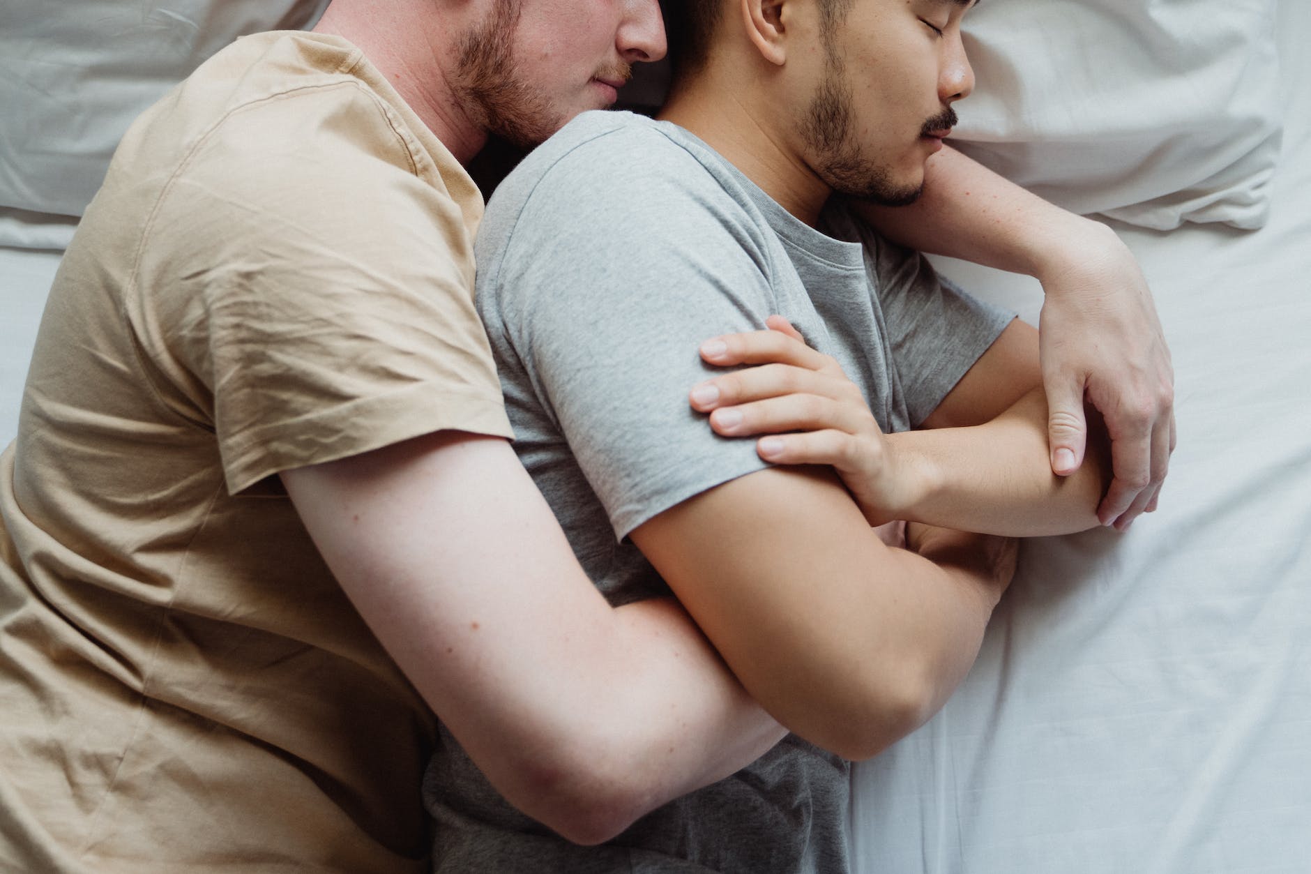 two men cuddling in bed