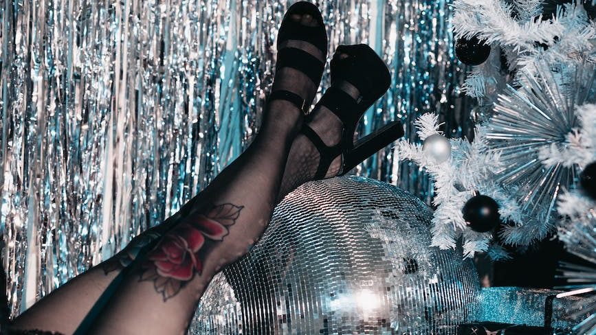 woman in high heels resting her legs on a disco ball