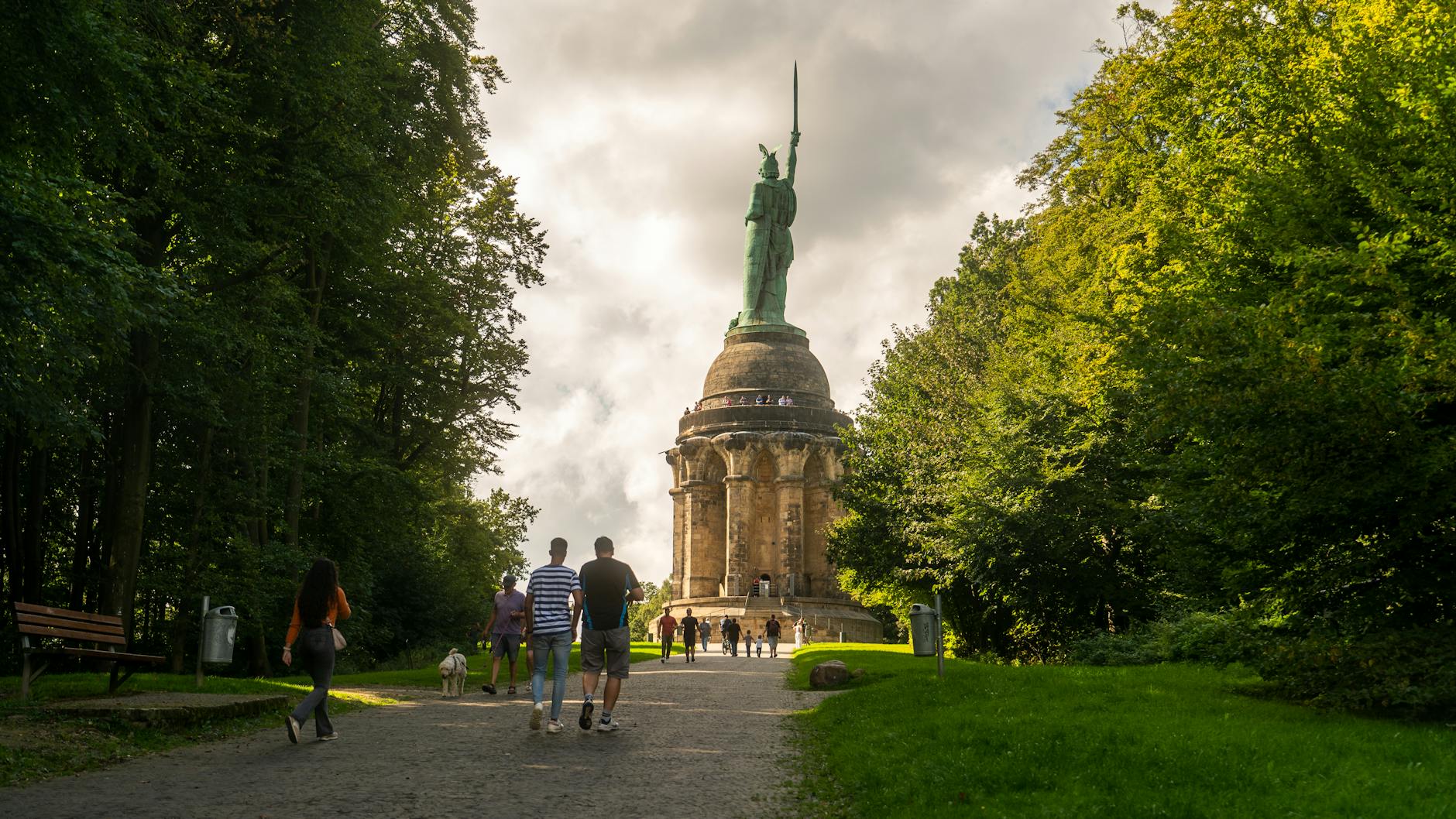 view of people walking in a park with the hermannsdenkmal monument located near detmold in germany