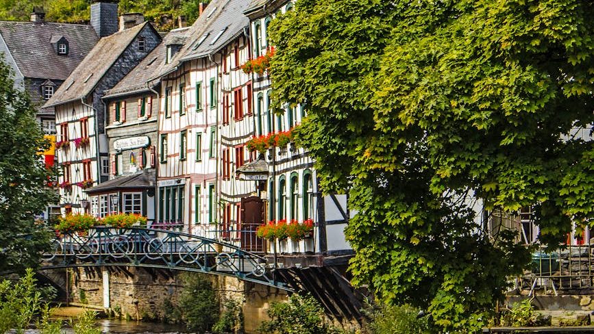 concrete houses near green trees and stream