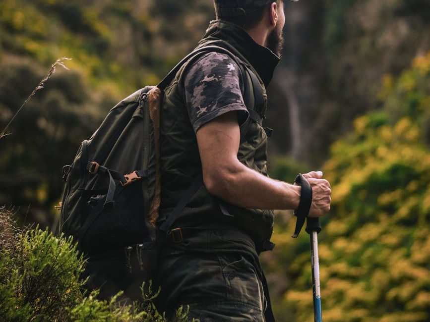 man wearing cap and crew neck shirt standing in the middle of forest