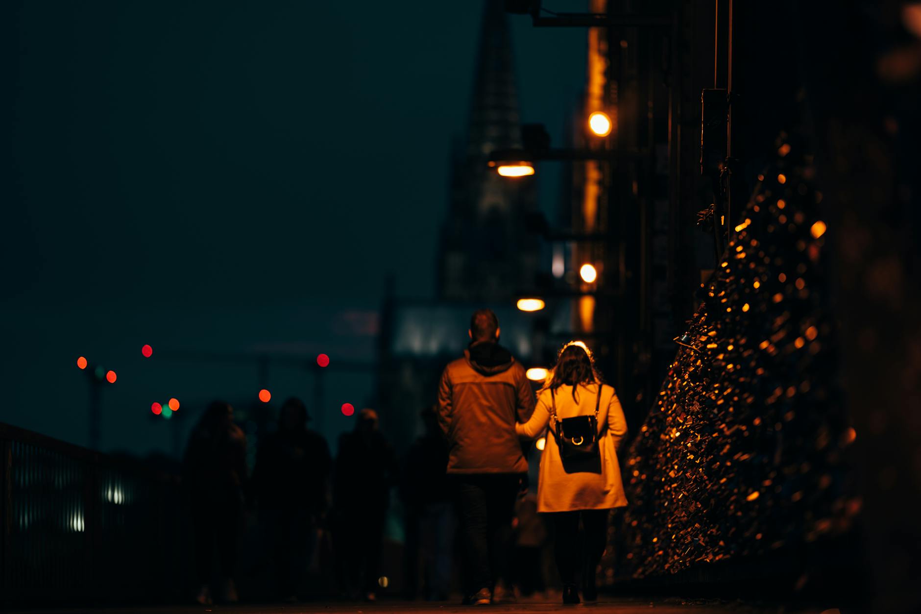 a couple walking on sidewalk of a street during night time