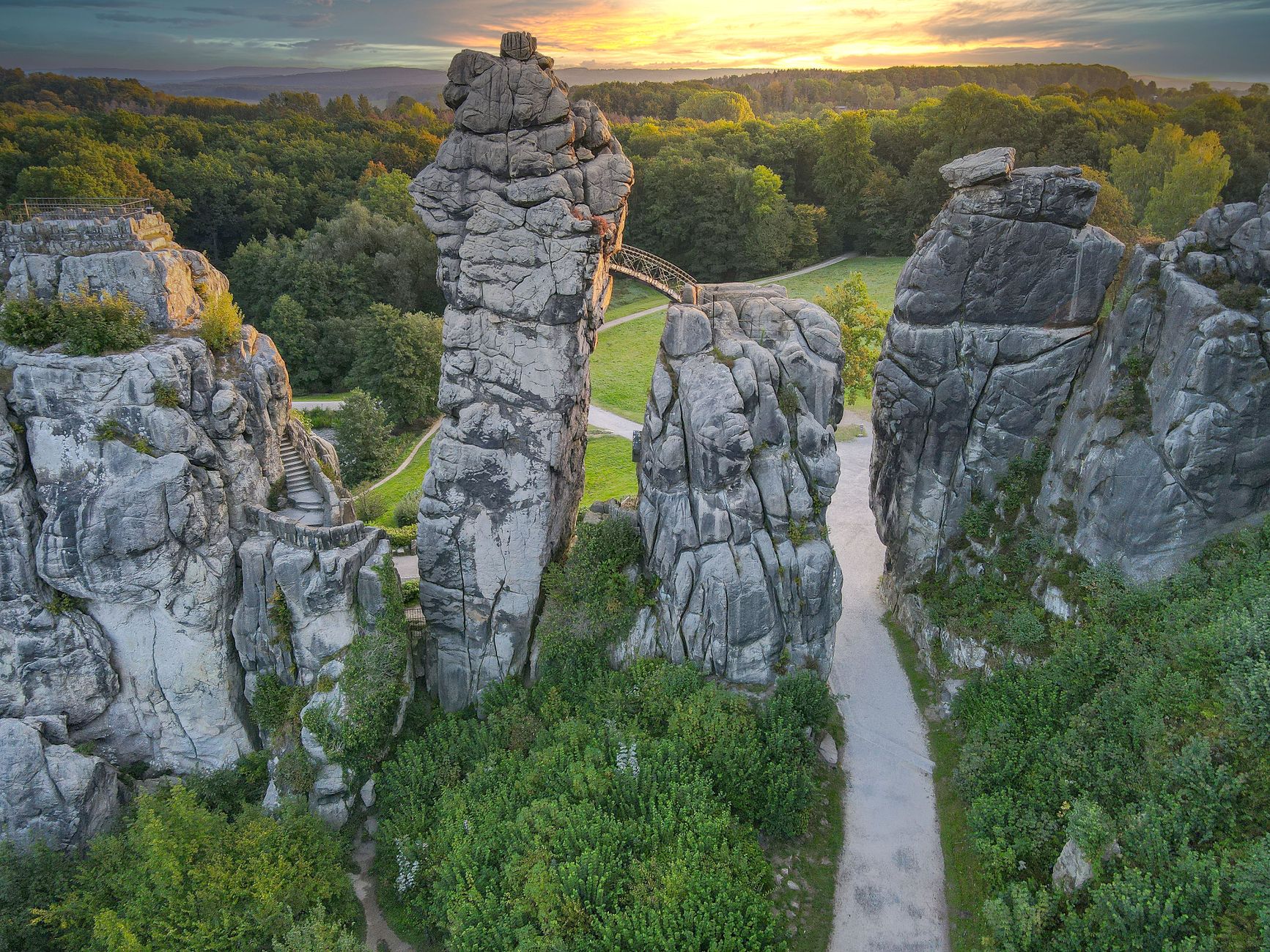 gray rock formations on green grass field near the forest